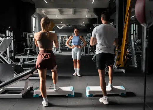 People doing step aerobics workout in modern gym with various gym equipment