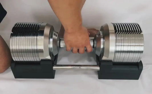 Adjustable dumbbell being set up for a workout, ideal gym equipment for versatile strength training and clutter-free space.