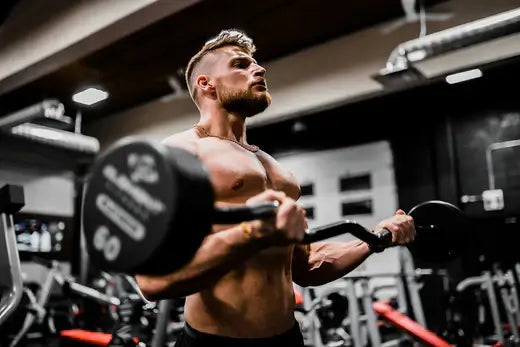 Bodybuilder performing bicep curls with adjustable dumbbell in gym environment