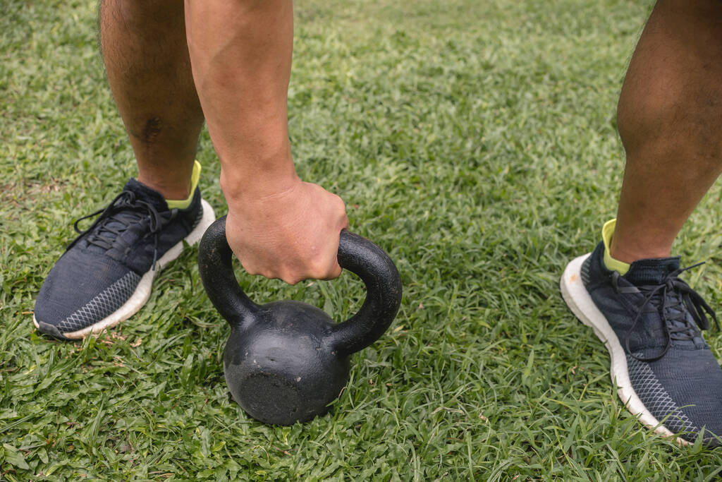 male picks kettlebell garden